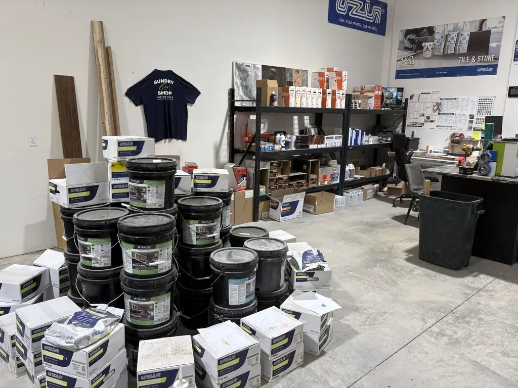 Sundry Pro Shop stock room in Columbia Falls, MT with Uzin grout boxes, Taylor Dynamic adhesive pails and WarmWire heat kits behind the Pro Desk