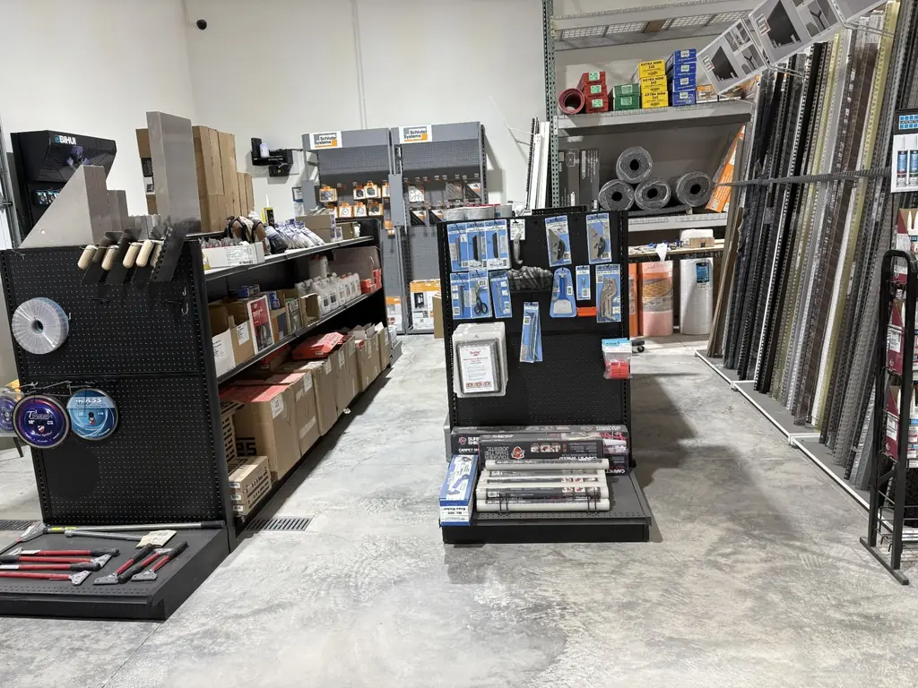 Main aisle inside Sundry Pro Shop showing shelving stocked with flooring tools, trim profiles and jobsite supplies