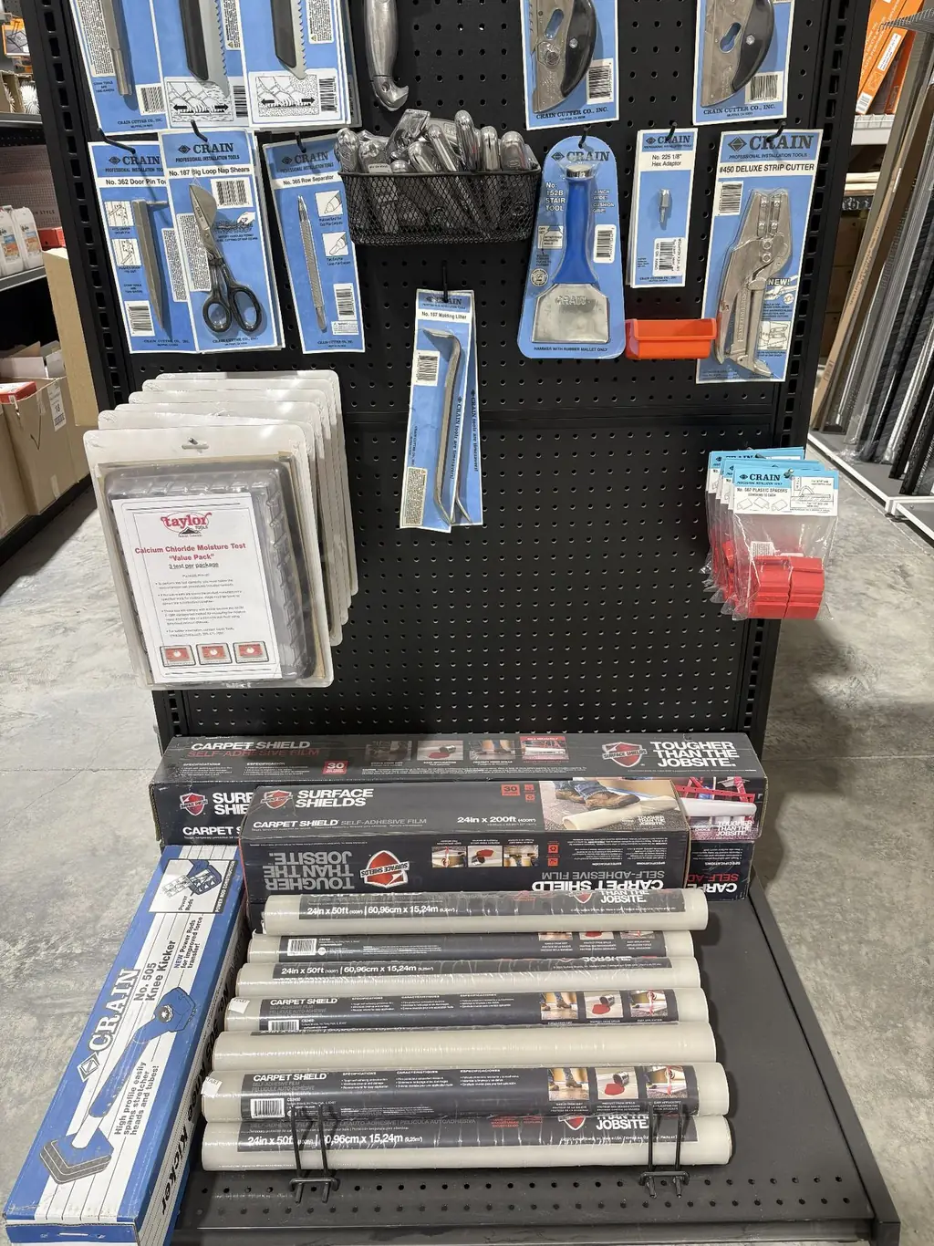 Crain installation tool pegboard at Sundry Pro Shop with strip cutters, nap shears, stair tools, knee kicker, Taylor moisture tests and Surface Shields carpet shield rolls
