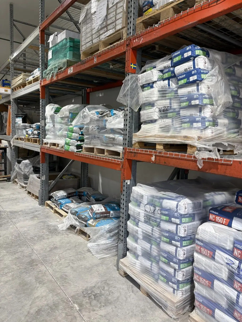 Warehouse racking at Sundry Pro Shop holding pallets of Laticrete and Uzin cementitious products including CX 20 and NC 150 F