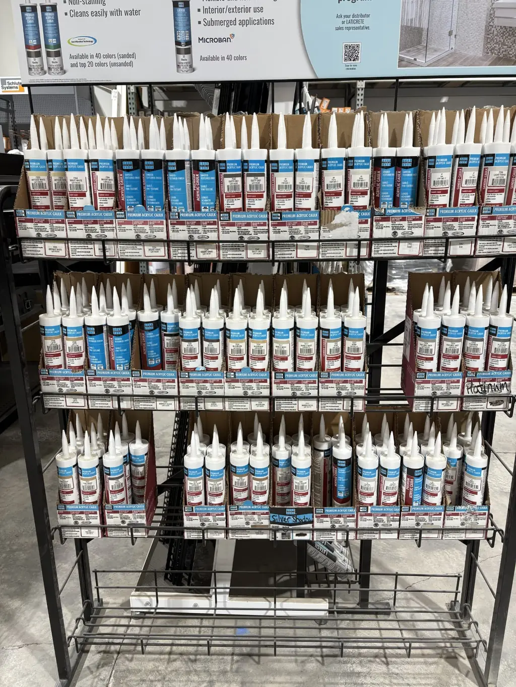 Laticrete premium acrylic caulk color rack at Sundry Pro Shop showing sanded and unsanded colors including Antique White, Dusty Grey, Latte, Mushroom, Natural Grey and Platinum