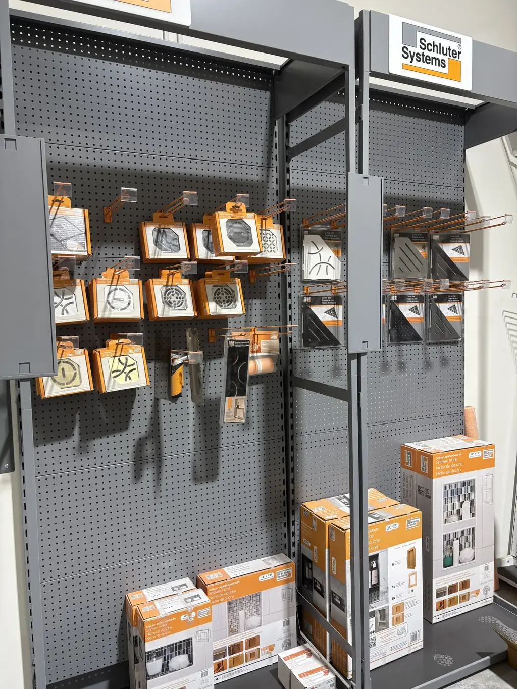 Schluter Systems display at Sundry Pro Shop with KERDI-DRAIN grates, corner shelves and KERDI-BOARD-SN shower niches