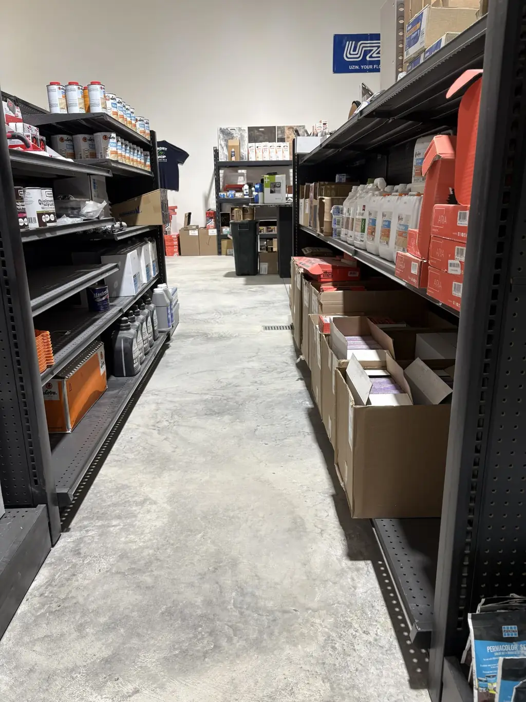 Aisle inside Sundry Pro Shop in Columbia Falls, MT stocked with Loba finishes and stains, Masterline sealers, Aria underlayment and Laticrete PERMACOLOR grout